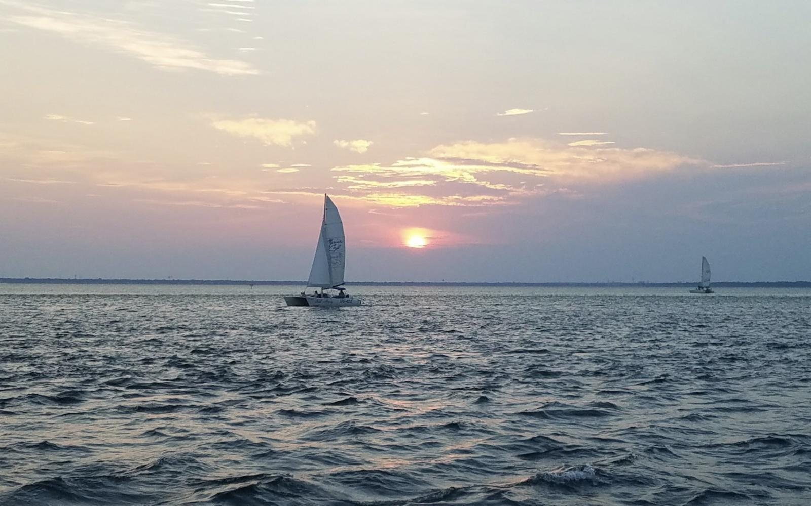 Catamaran sailing on the bay at sunset